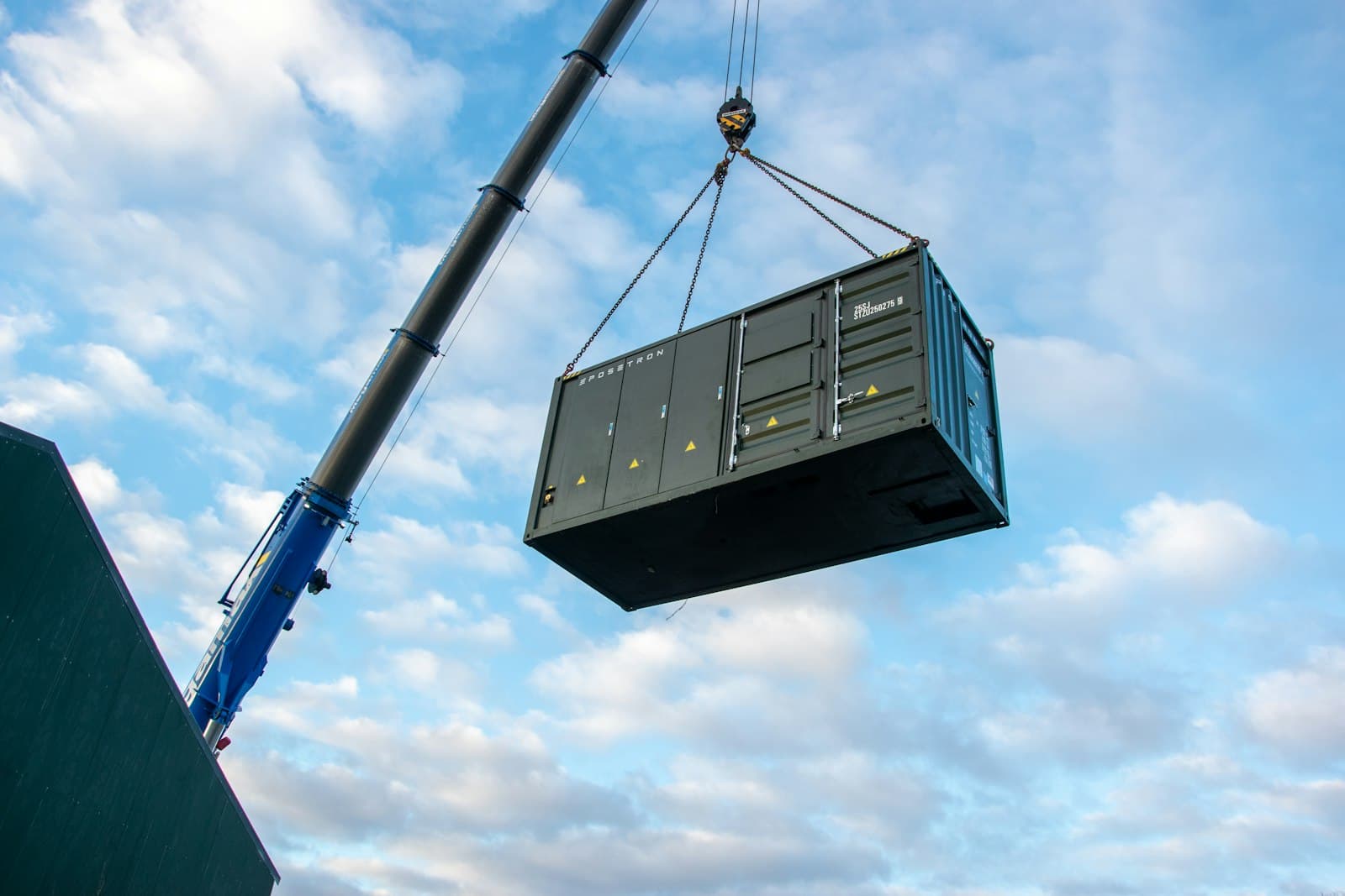 A crane lifting a shipping container against the sky